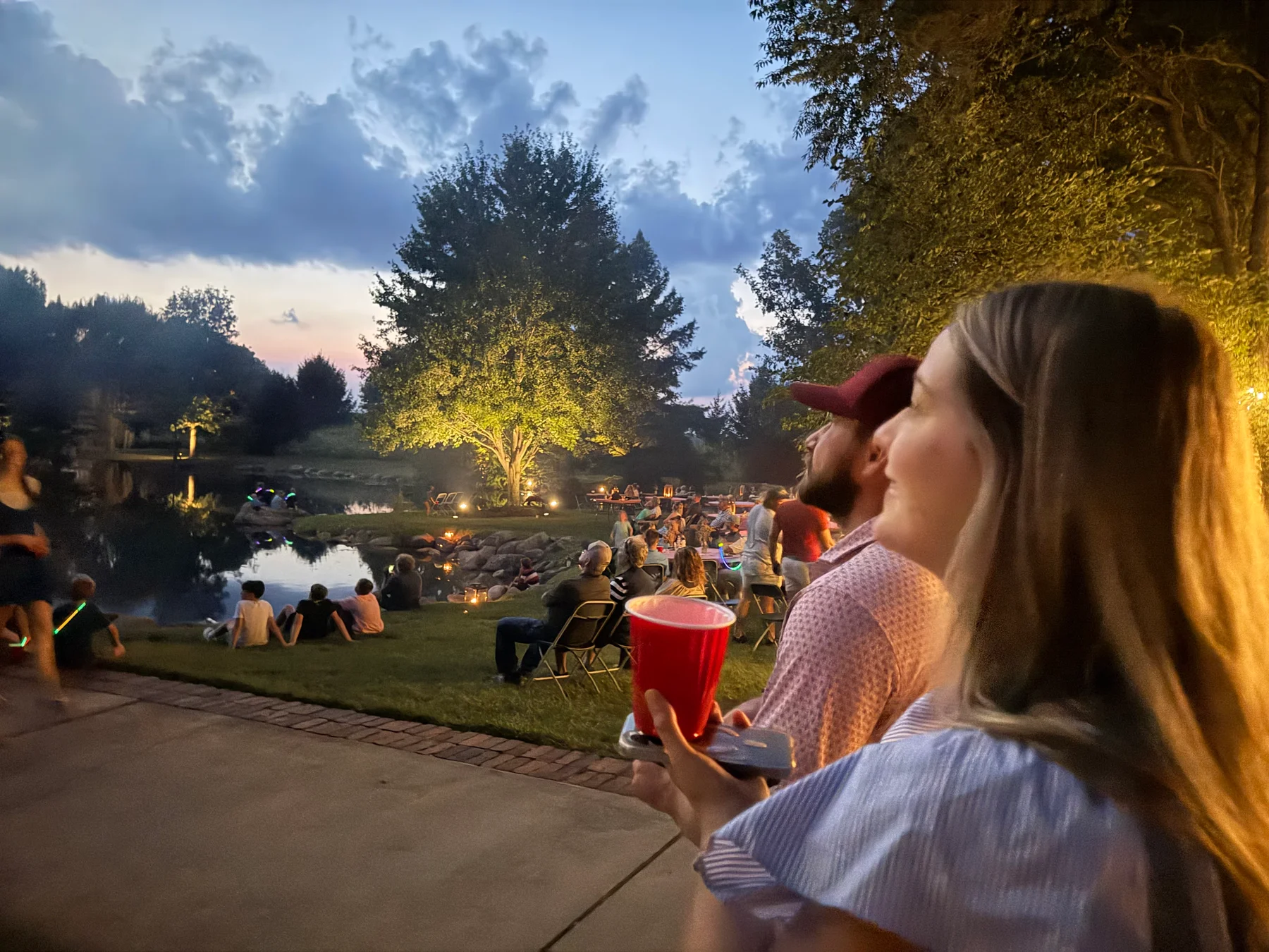 Guests enjoying the fish fry beside the pond at dusk